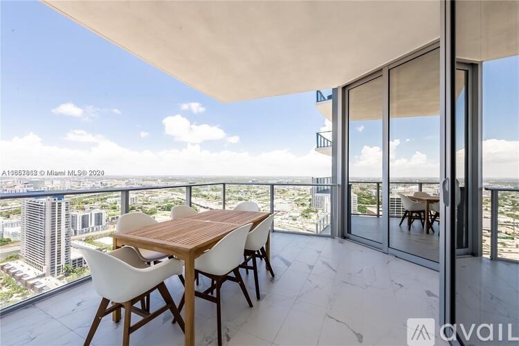 A balcony with a table and chairs overlooking a cityscape.