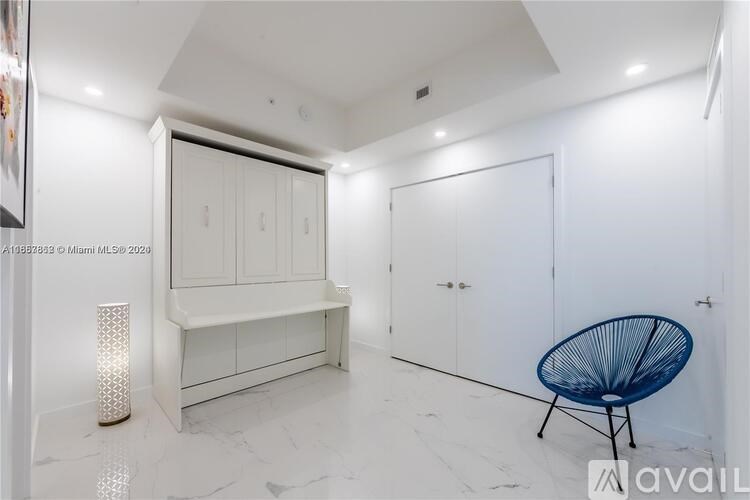 A white room with a blue chair and a white cabinet.