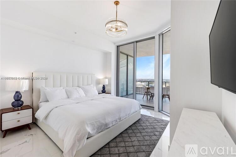 A bedroom with a large bed, a chandelier, and a balcony view.