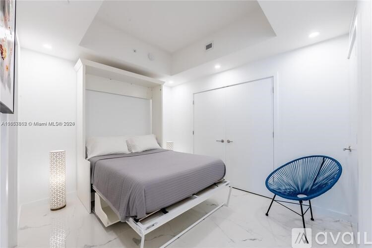 A bedroom with a bed, chair, and a painting on the wall.