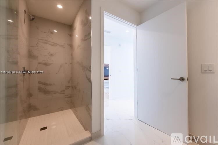 A bathroom with marble walls and a walk-in shower.