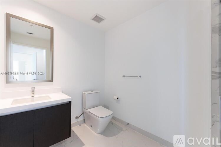 A bathroom with a toilet, sink, and mirror.