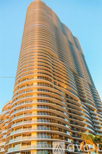 A tall building with a curved facade and balconies on each floor.