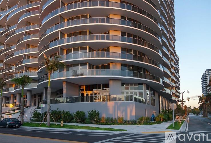 A modern apartment building with balconies and palm trees in front.