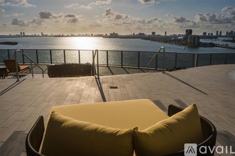 A sunny day at the waterfront with a yellow cushioned chair in the foreground.