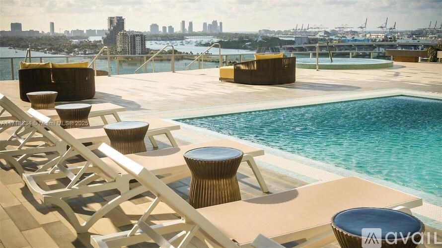 A poolside area with sun loungers and tables overlooking a city skyline.