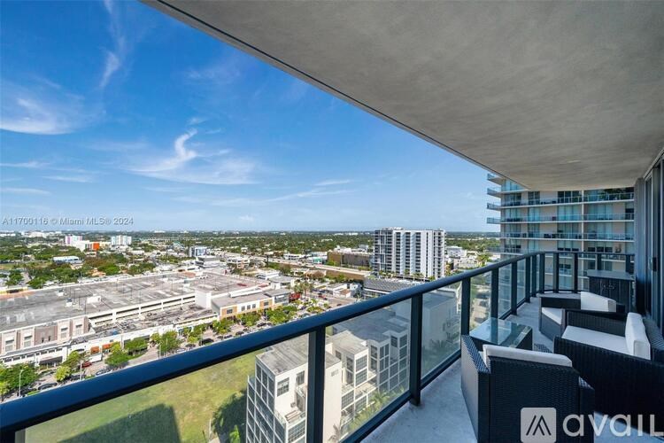 A balcony overlooks a cityscape with buildings and greenery.