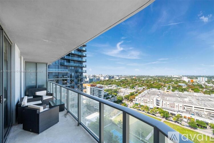 A balcony with a table and chairs overlooks a cityscape.