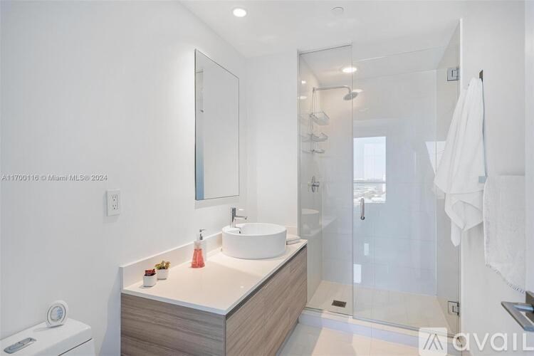 A modern bathroom with a white sink and a large mirror.