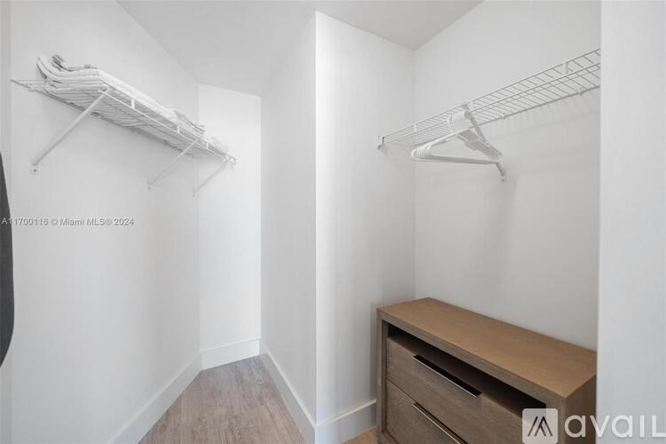 A small, white closet with a bench and two shelves.