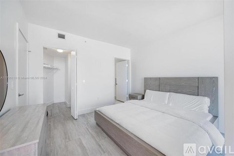 A bedroom with a large bed and a walk-in closet.