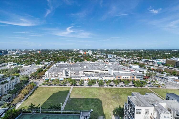 A large building with a green lawn in front is surrounded by other buildings.