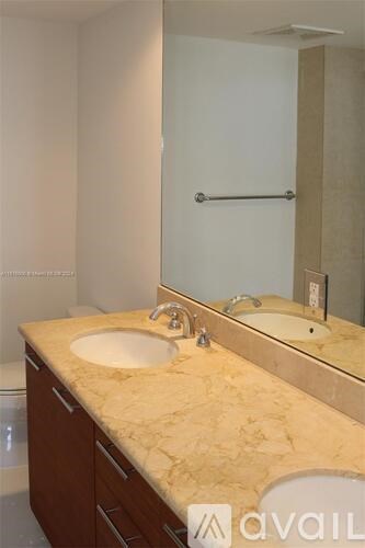 A bathroom with a marble countertop and a mirror above the sink.