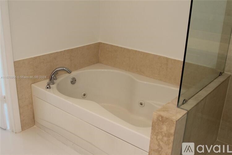 A white bathtub with a glass shower door.