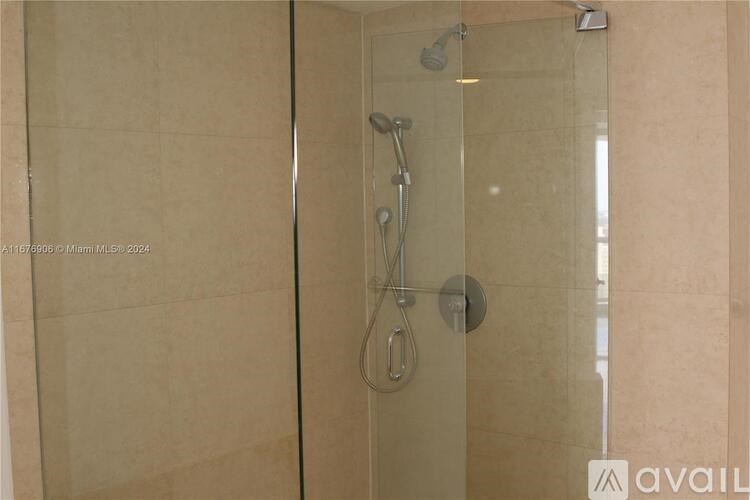 A shower area with a glass door and a shower head.