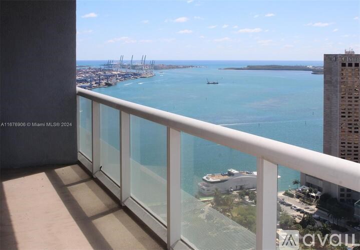 A balcony with a glass railing overlooking a marina with boats.