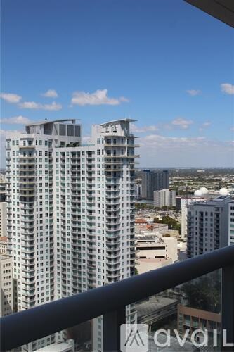 A tall building with balconies overlooks a cityscape.