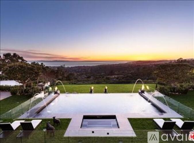 A large outdoor swimming pool surrounded by a grassy area and trees.