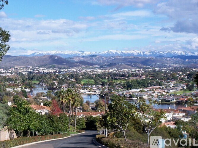 A road with a sign that says "avail" in front of a town with mountains in the background.