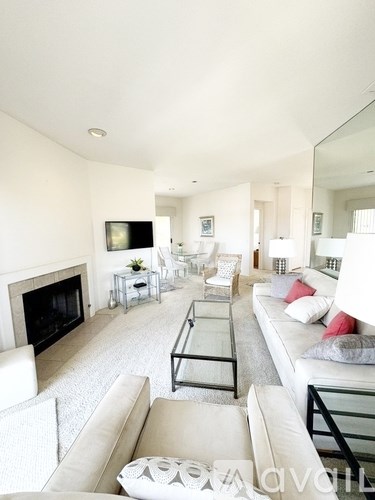 A living room with a fireplace and a glass coffee table.