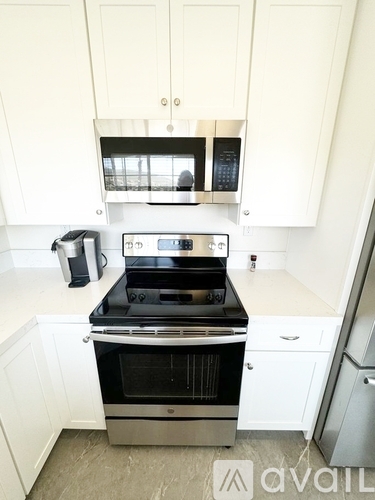 A modern kitchen with white cabinets and stainless steel appliances.