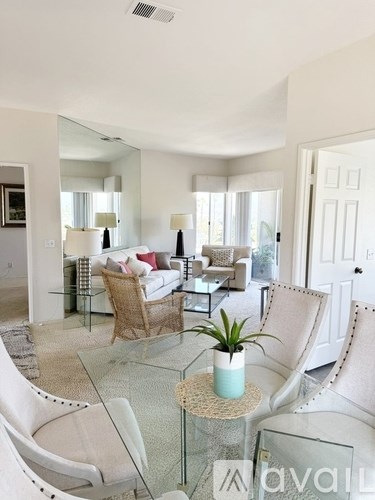 A living room with a glass table and white chairs.
