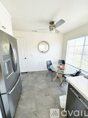 A kitchen with a stainless steel refrigerator and a table with chairs.