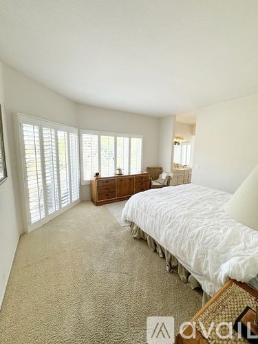 A bedroom with a large bed and a dresser with a mirror.