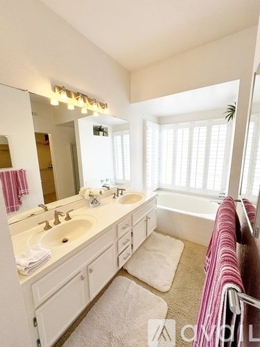 A bathroom with a white vanity and a pink towel.