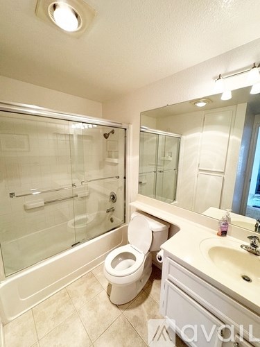 A white toilet sits in a bathroom next to a sink and a glass shower stall.