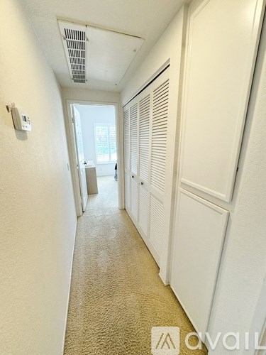 A hallway with white walls and carpeted floor.
