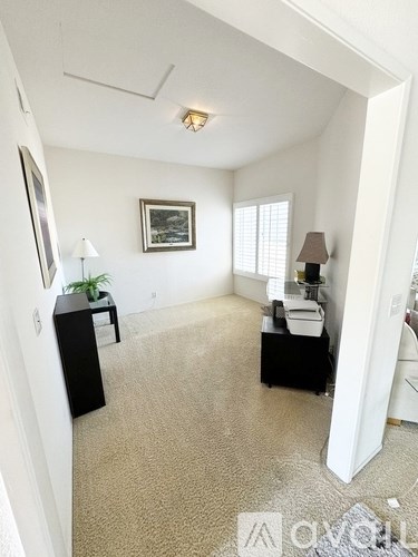 A room with a carpet floor, a ceiling fan, and a picture on the wall.
