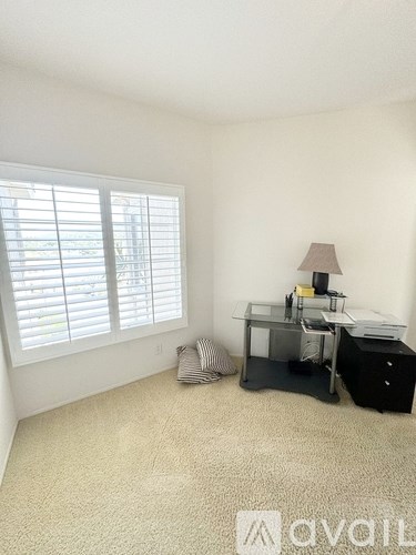 A room with a desk, chair, and window with blinds.
