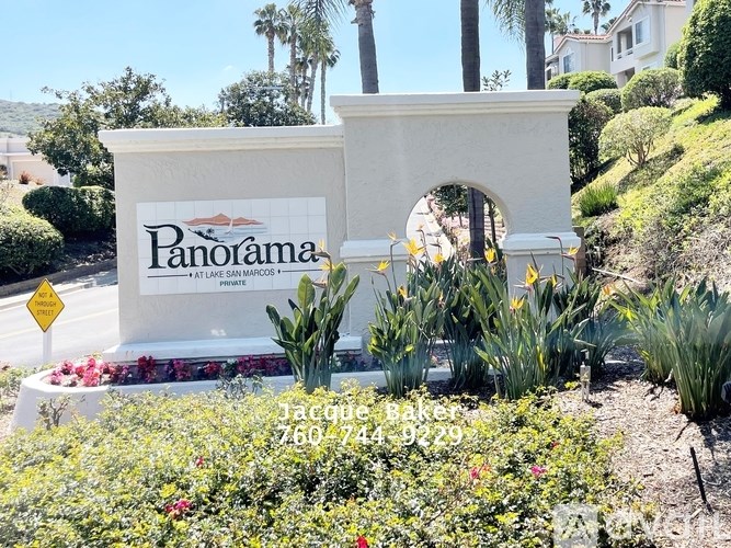 A sign for Panorama Vacation Rentals is surrounded by plants and flowers.