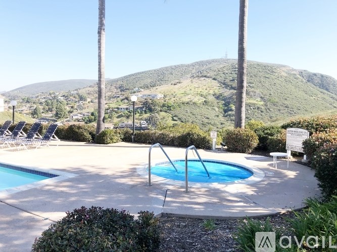 A pool surrounded by palm trees and bushes with a mountain in the background.