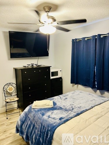 A bedroom with a bed, a dresser, a chair, and a ceiling fan.