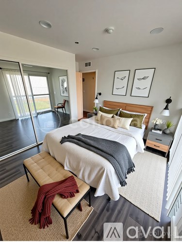 A bedroom with a large bed and a bench with a red blanket on it.