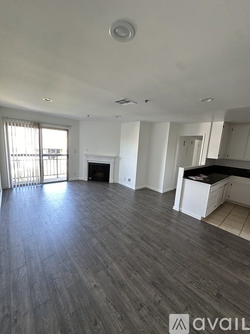 A spacious living room with a fireplace and a kitchen area in the background.