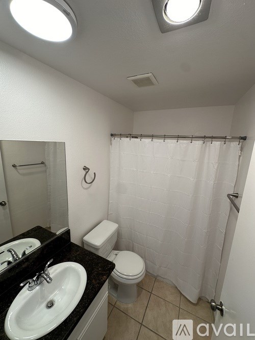 A bathroom with a toilet, sink, and shower curtain.