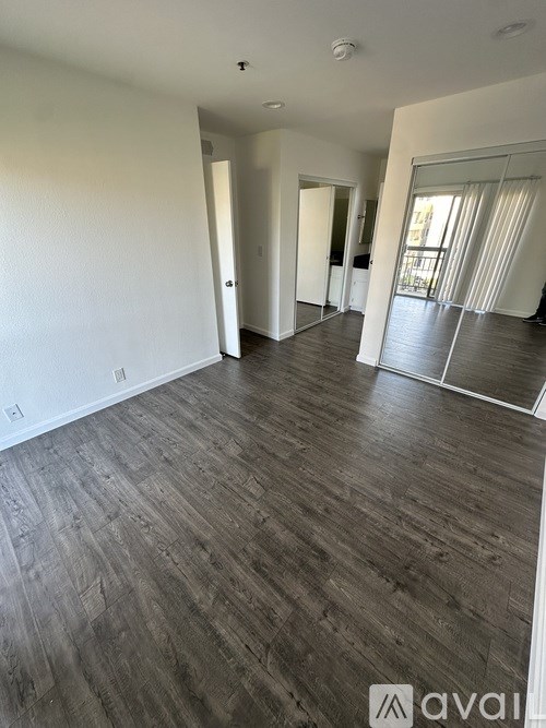 A spacious room with wood flooring and white walls.
