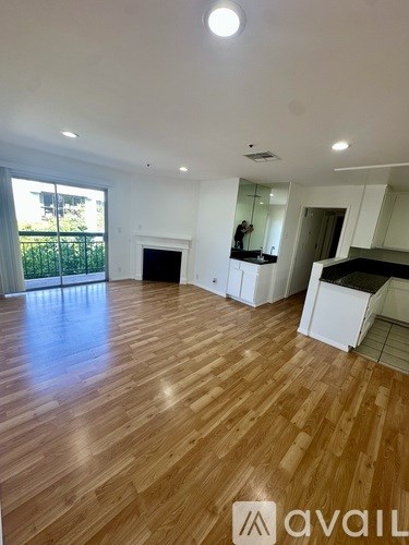 A spacious room with wood flooring and white walls.