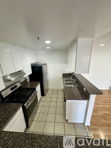A kitchen with black appliances and white cabinets.