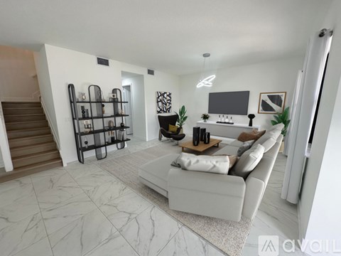 A modern living room with a white sofa and a TV on the wall.