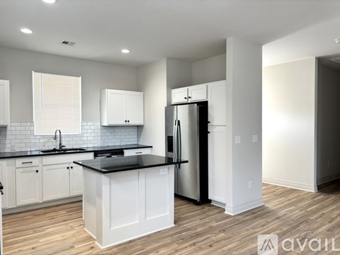 A kitchen with white cabinets and a black countertop.