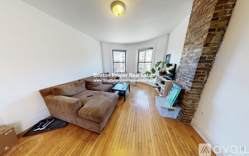 A living room with a brick column and hardwood floors.