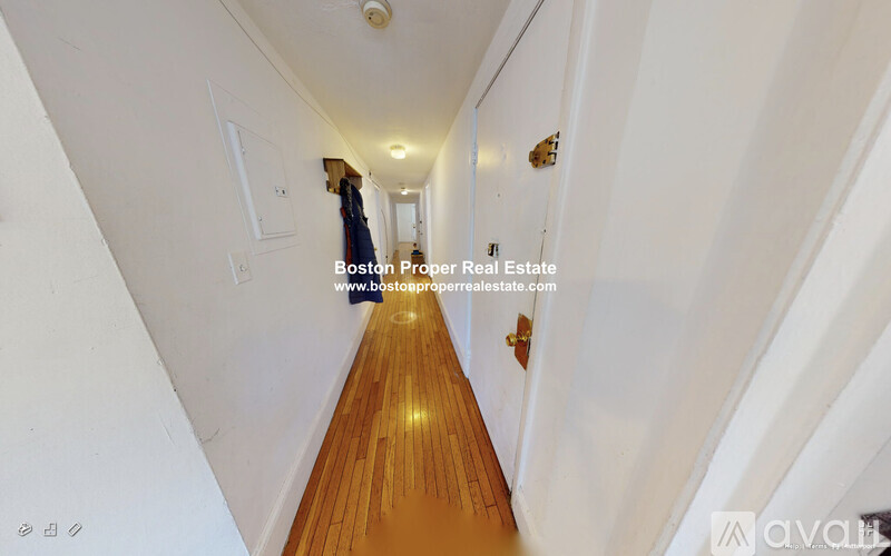 A long hallway with wooden floors and white walls.