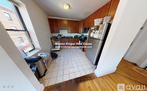A kitchen with a refrigerator, sink, and a window overlooking a street.