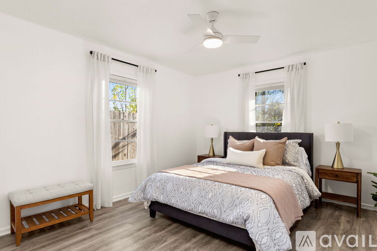 A bedroom with a large bed and a window with curtains.