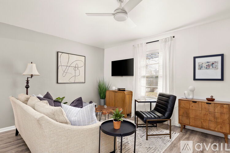 A living room with a beige couch, a black chair, a wooden cabinet, and a ceiling fan.