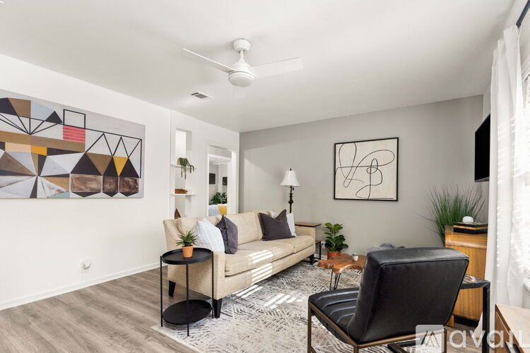 A living room with a couch, chair, and a painting on the wall.